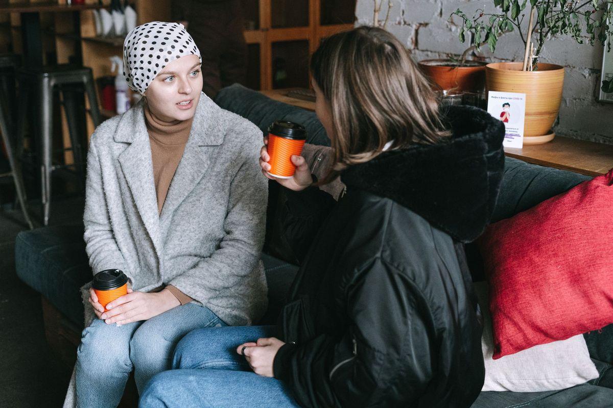 Two friends with hot drinks on a sofa